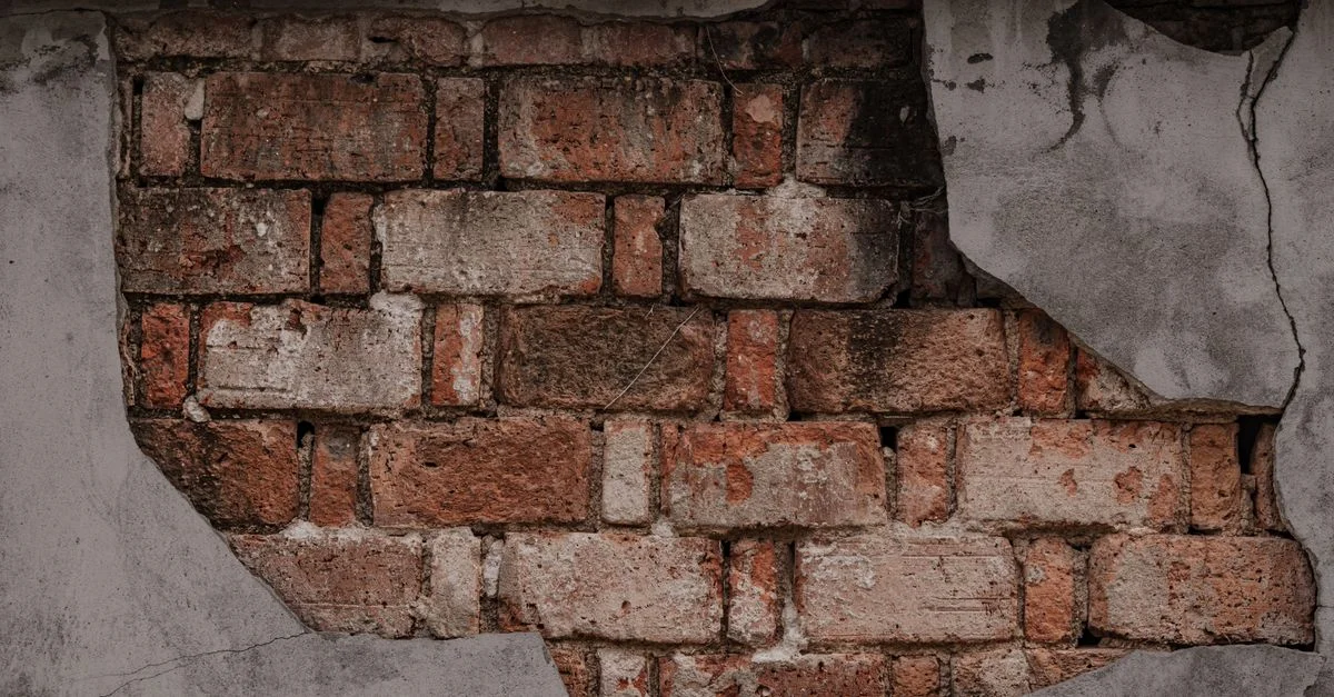 Gros plan sur un mur patiné par le temps, aux briques rustiques apparentes, illustrant une dégradation urbaine texturée.