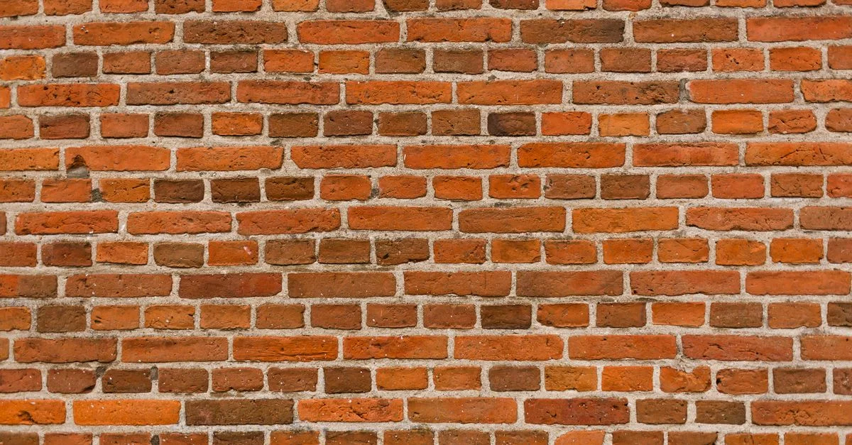 Vue rapprochée d'un mur en briques rouges classique créant un motif texturé.