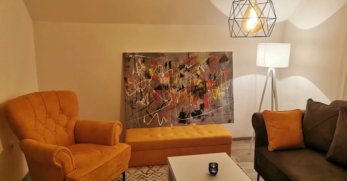 Salon moderne agréable avec un luminaire géométrique, de l'art mural abstrait et des meubles confortables.