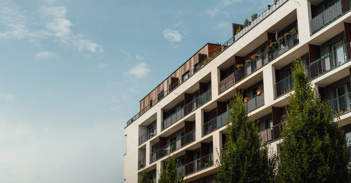 Immeuble d'appartement moderne et stylé sous un ciel bleu clair, mettant en avant des balcons et une architecture urbaine.