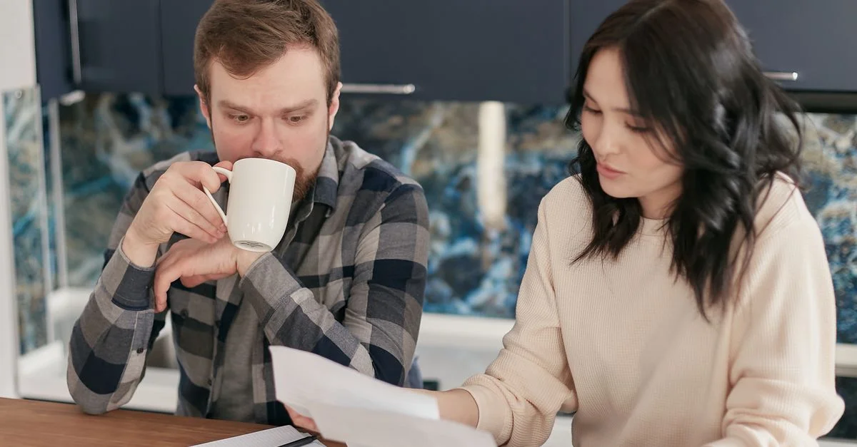 Un couple examinant des factures en utilisant une calculatrice et des documents, symbolisant la planification financière à domicile.