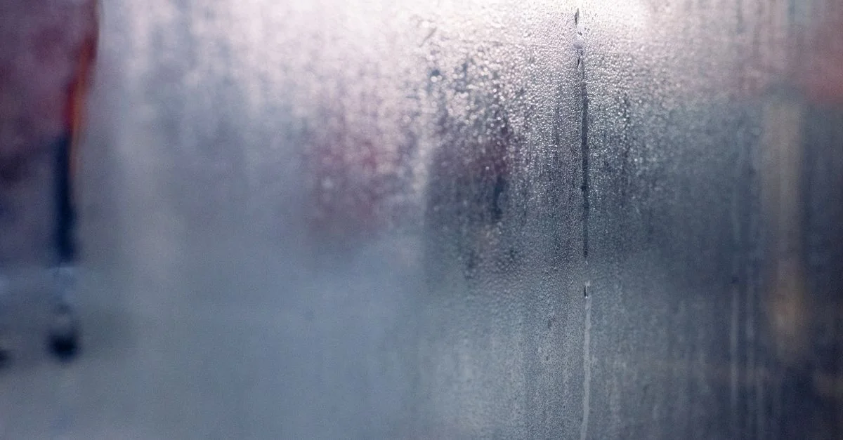 Des gouttes d'humidité sur une fenêtre embrumée créent une atmosphère mystérieuse et sereine.