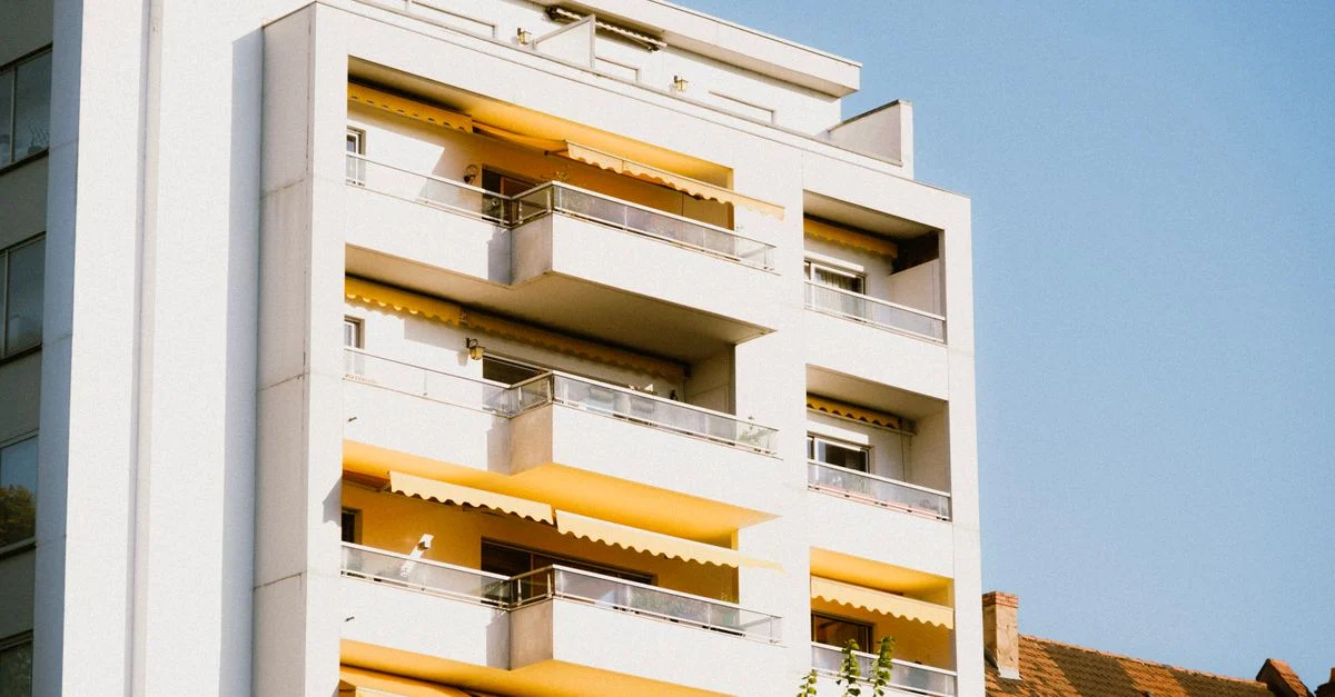 Vue en contre-plongée d'un immeuble d'appartements contemporain avec des balcons jaunes contre un ciel dégagé.