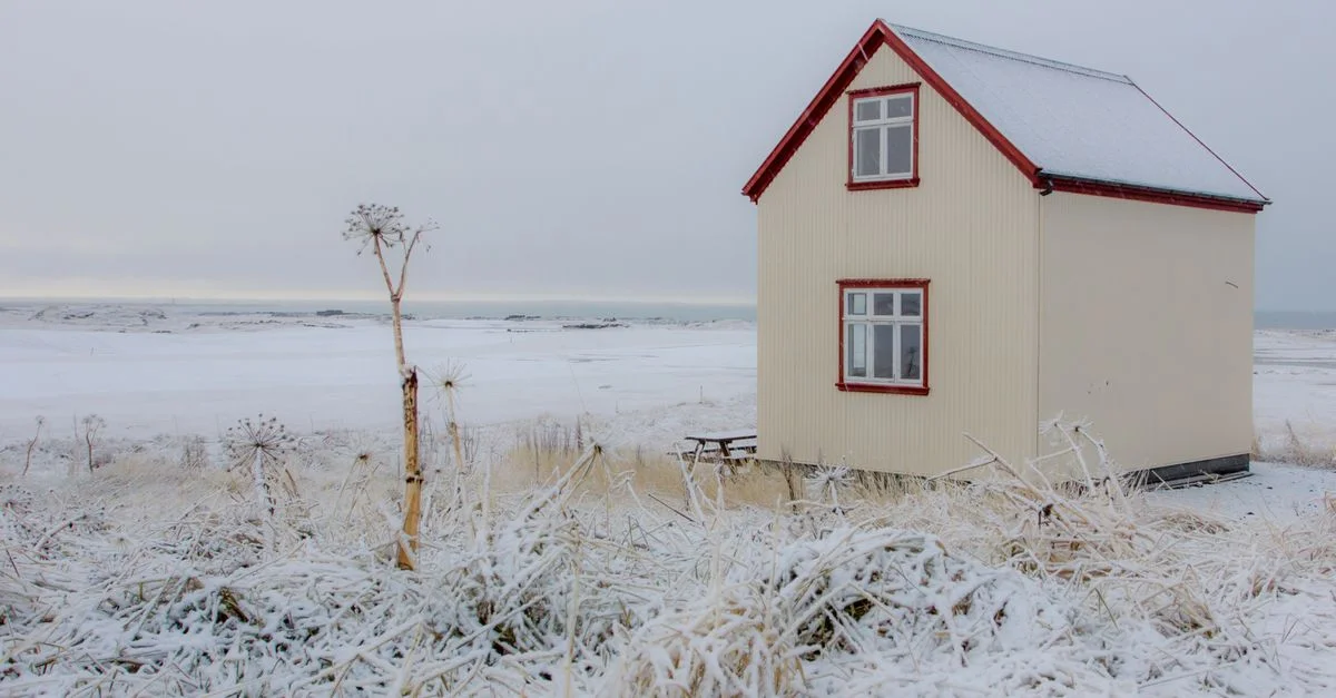 Une cabane confortable entourée de neige à Vogar, en Islande, capture la beauté sereine de l'hiver.