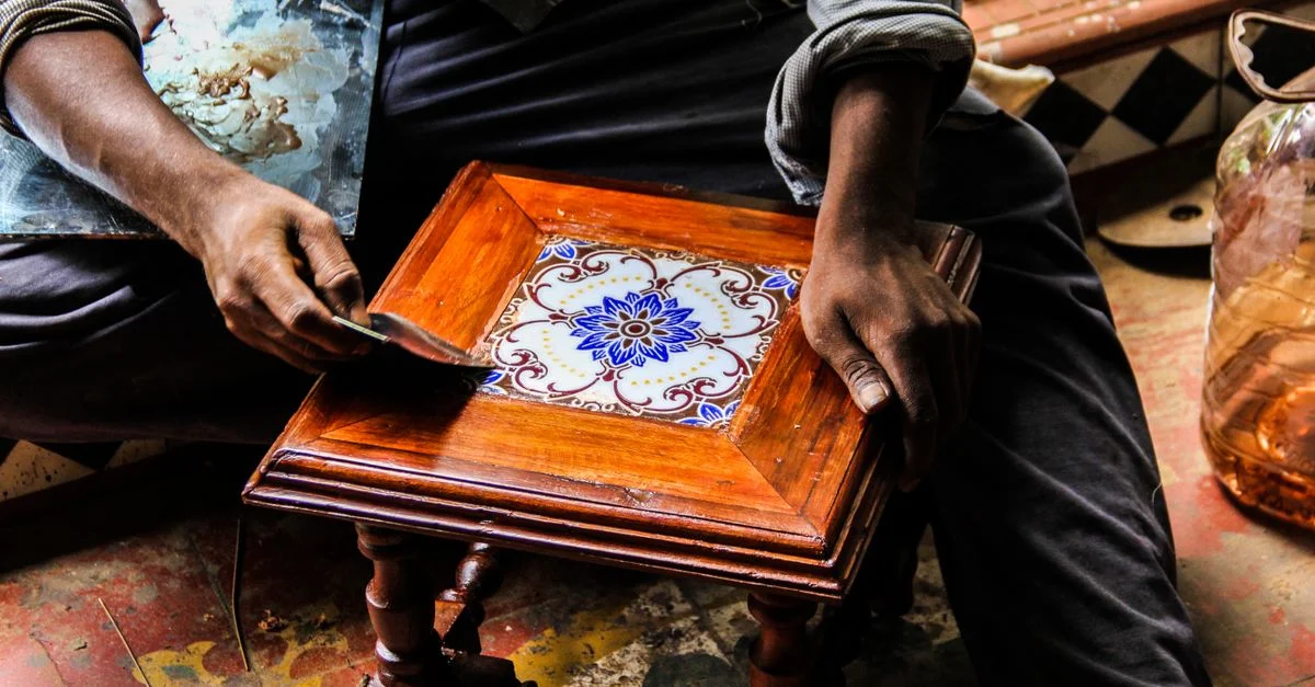 Gros plan sur un artisan façonnant habilement un panneau en bois décoratif avec un design de marqueterie complexe.