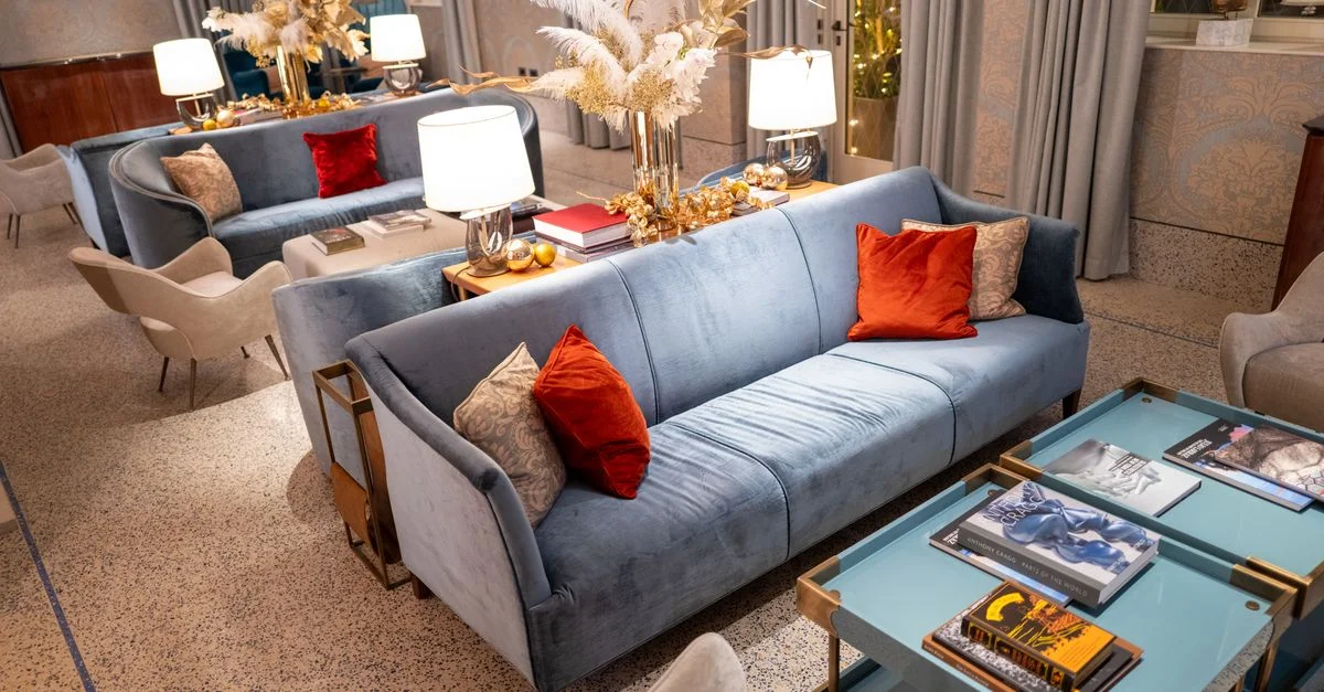 Salon de luxe avec des canapés bleus, décor élégant et éclairage stylé créant une ambiance chaleureuse.